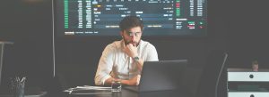 Cover Image for Crypto Market concepts Man deep in thought in front of laptop with trading image in background